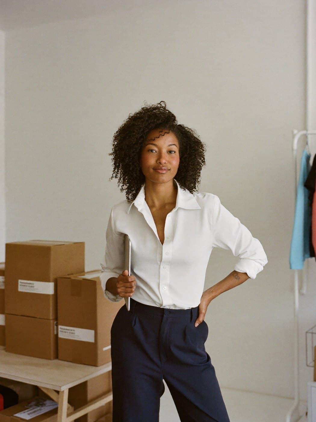 Fundadora de uma marca de roupas no estúdio, ao lado das caixas prontas para envio